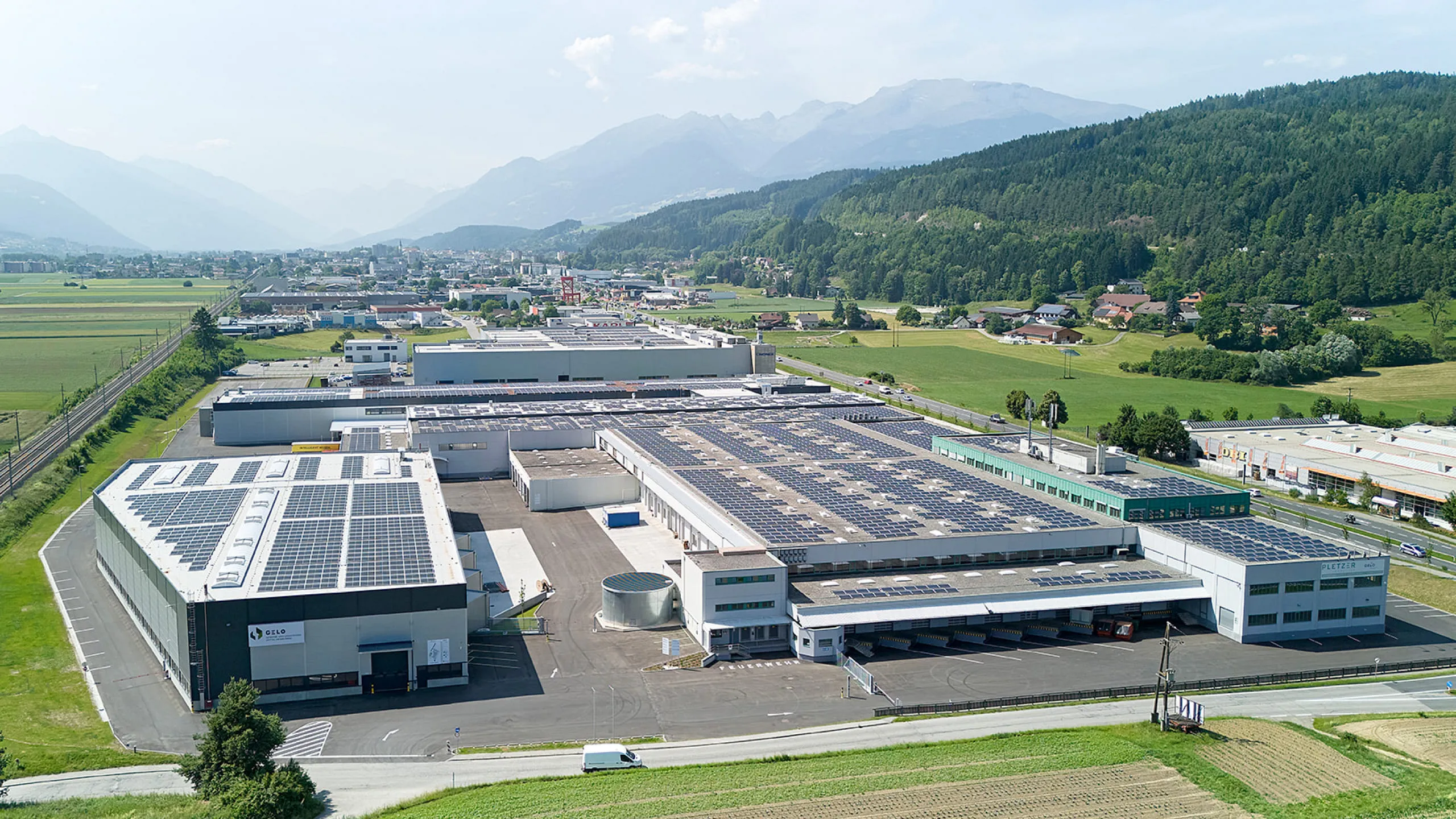 Großes Industrie- und Logistikareal von Pletzer Immobilien mit Solardächern und Alpenpanorama.
